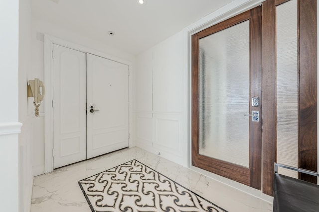 foyer entrance with a decorative wall and marble finish floor