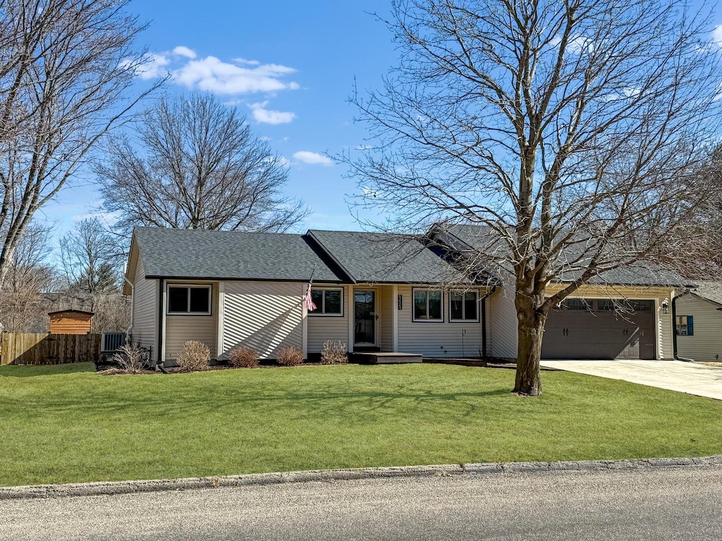 ranch-style house featuring an attached garage, driveway, fence, and a front lawn