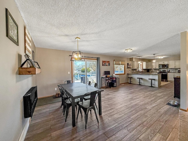 dining area with baseboards, a textured ceiling, an inviting chandelier, and wood finished floors