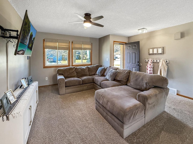 living room with a ceiling fan, carpet flooring, a textured ceiling, and baseboards