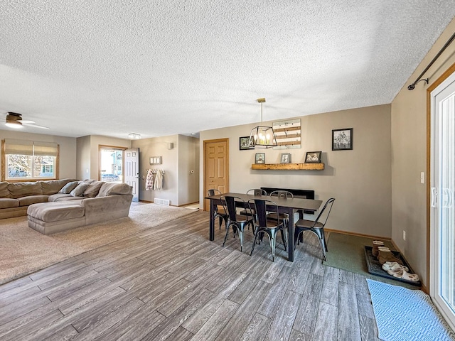 dining space featuring visible vents, ceiling fan, a textured ceiling, wood finished floors, and baseboards