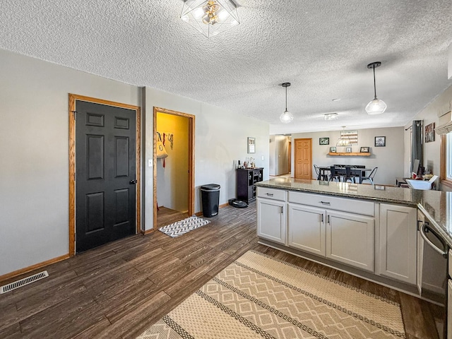 kitchen with pendant lighting, visible vents, dark wood-type flooring, a peninsula, and baseboards