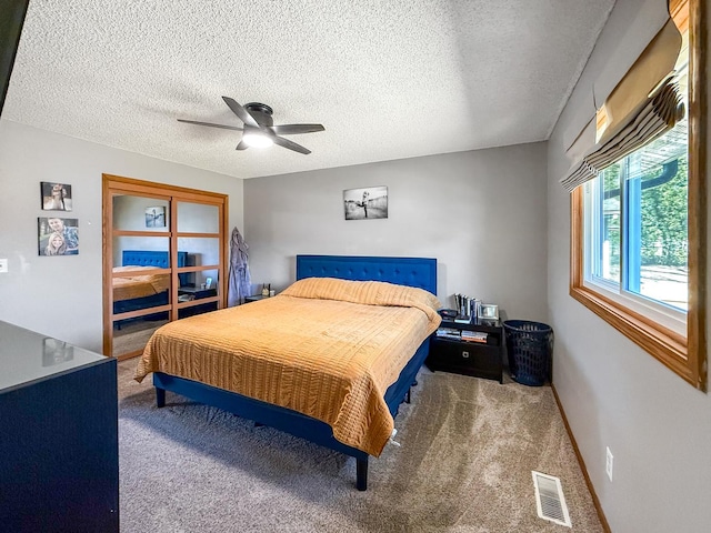 carpeted bedroom featuring a textured ceiling, ceiling fan, visible vents, and baseboards