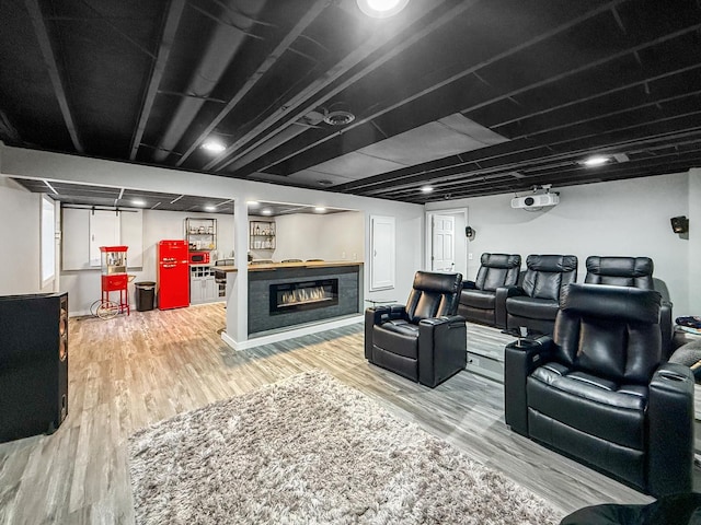 living area featuring light wood-style flooring and a glass covered fireplace