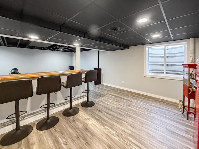 bar featuring visible vents, a bar, baseboards, and wood finished floors