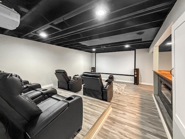 home theater room featuring wood finished floors, visible vents, and baseboards