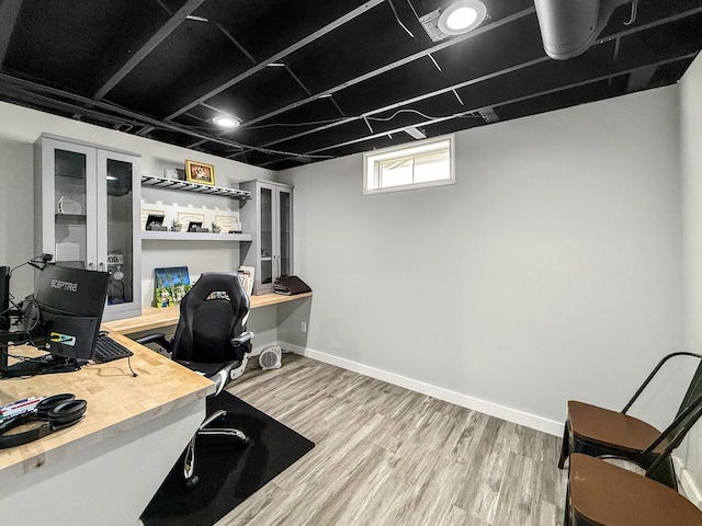 office space with baseboards, built in desk, and light wood-style floors