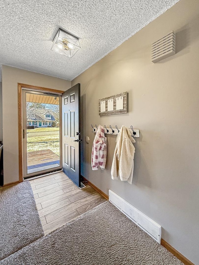 interior space featuring light wood finished floors, baseboards, visible vents, and a textured ceiling