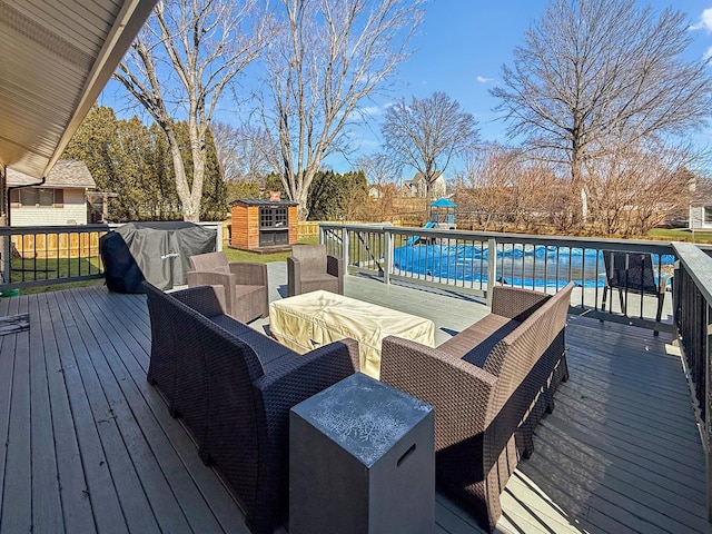 wooden terrace with a playground, an outdoor living space, an outdoor structure, and a pool