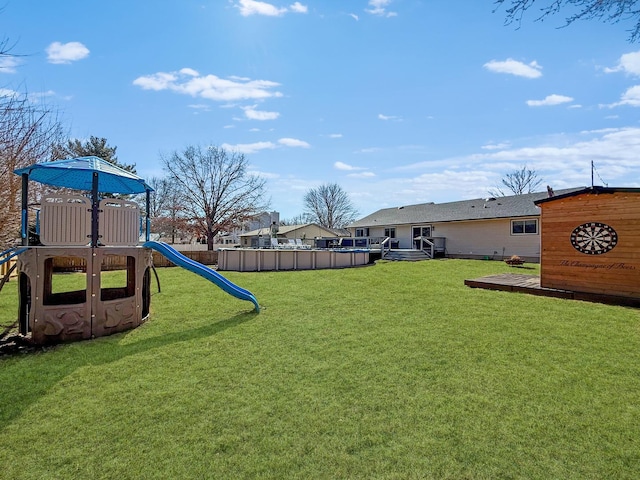 view of jungle gym featuring a deck, a lawn, and an outdoor pool