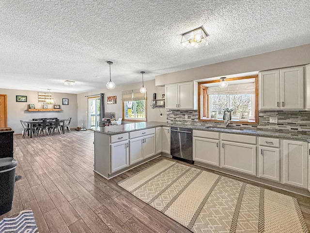 kitchen with tasteful backsplash, a sink, wood finished floors, dishwasher, and a peninsula