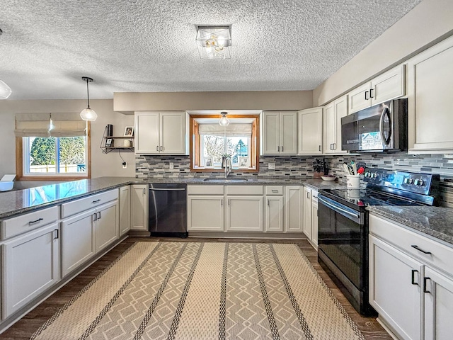 kitchen with a peninsula, a healthy amount of sunlight, appliances with stainless steel finishes, and a sink