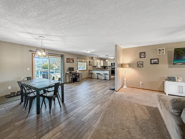 dining area with a textured ceiling, baseboards, wood finished floors, and a notable chandelier