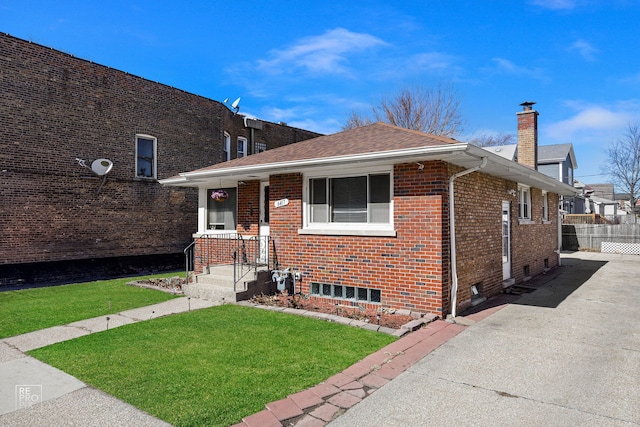 view of front of house with brick siding, a chimney, a shingled roof, fence, and a front lawn