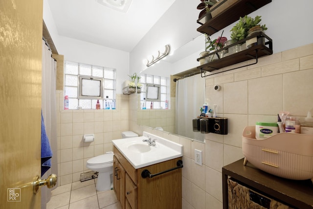 bathroom featuring tile walls, toilet, vaulted ceiling, vanity, and tile patterned floors