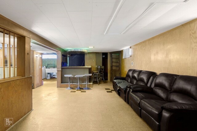 living room featuring wooden walls, washer / clothes dryer, and tile patterned floors