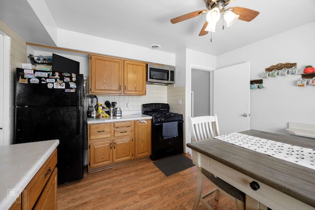 kitchen featuring light wood-style flooring, light countertops, black appliances, tasteful backsplash, and brown cabinetry