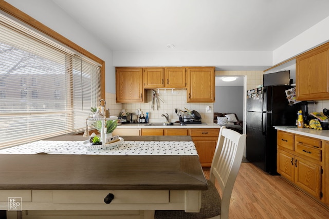 kitchen with light wood-style flooring, light countertops, a sink, and freestanding refrigerator