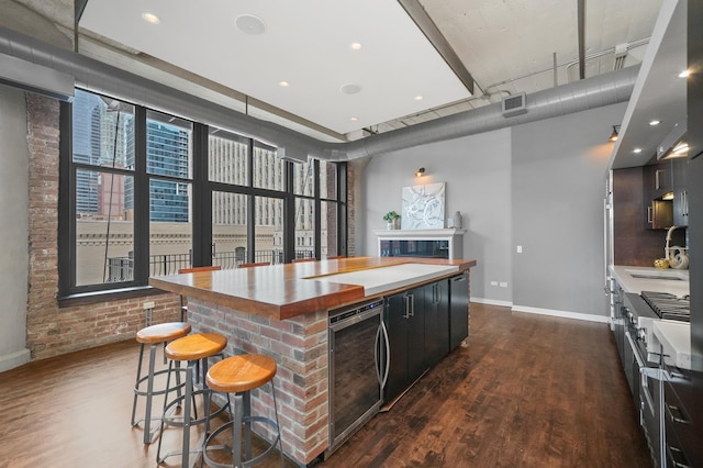 kitchen featuring wine cooler, a sink, visible vents, a center island, and dark wood finished floors