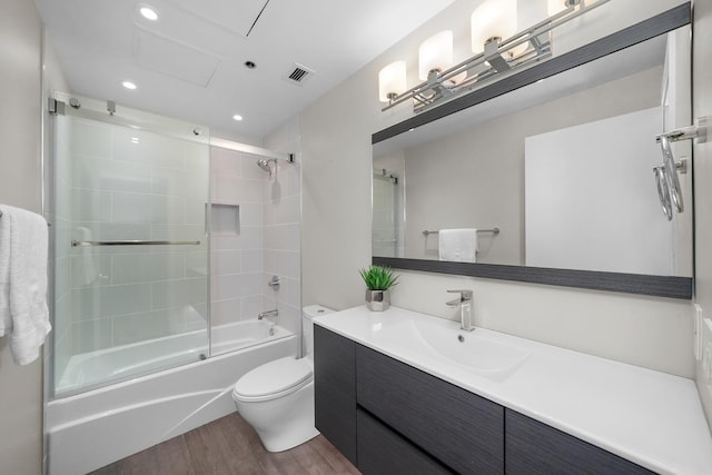 bathroom featuring bath / shower combo with glass door, toilet, wood finished floors, vanity, and recessed lighting