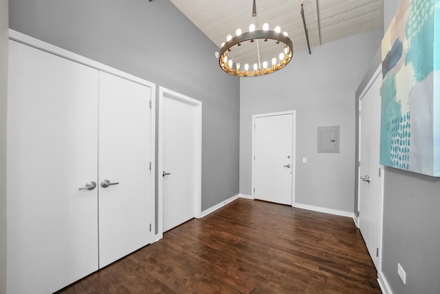 entrance foyer featuring electric panel, baseboards, wood finished floors, a high ceiling, and a notable chandelier