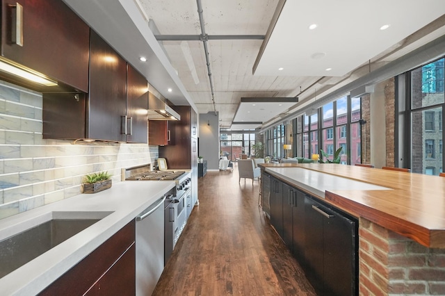 kitchen featuring dark wood finished floors, backsplash, appliances with stainless steel finishes, open floor plan, and a sink