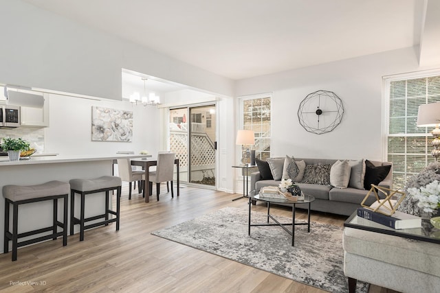 living room with light wood-style floors, a healthy amount of sunlight, and a notable chandelier