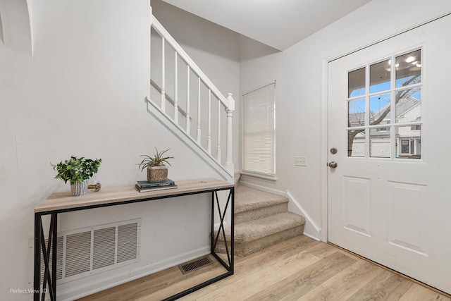 entrance foyer featuring stairs, baseboards, visible vents, and light wood-style floors