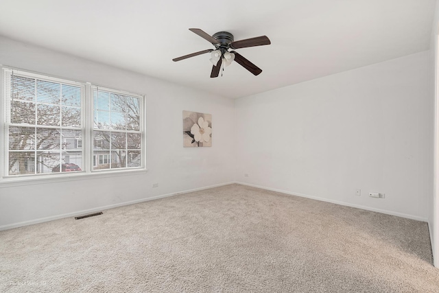 carpeted empty room with baseboards, visible vents, and ceiling fan