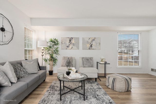 living room with baseboards, visible vents, and light wood finished floors