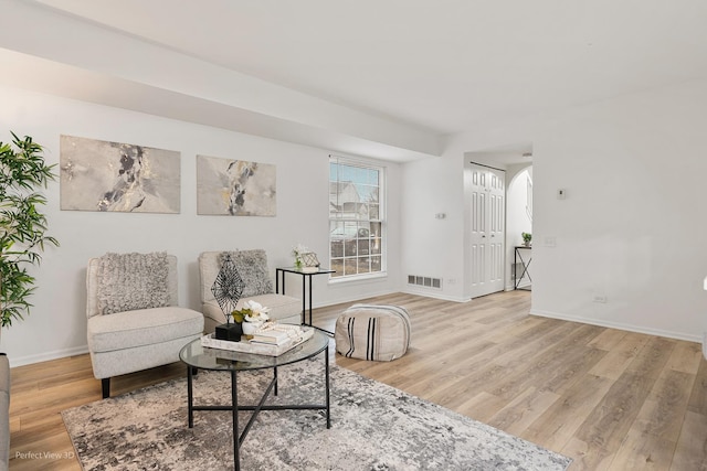 living area featuring light wood-style floors, visible vents, and baseboards