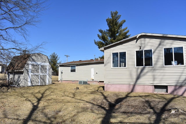 back of property with a yard, a shed, and an outbuilding