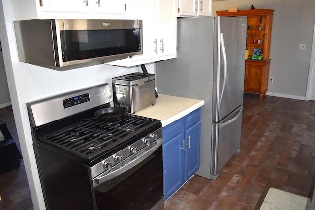 kitchen with blue cabinetry, stainless steel appliances, light countertops, dark wood-type flooring, and white cabinetry