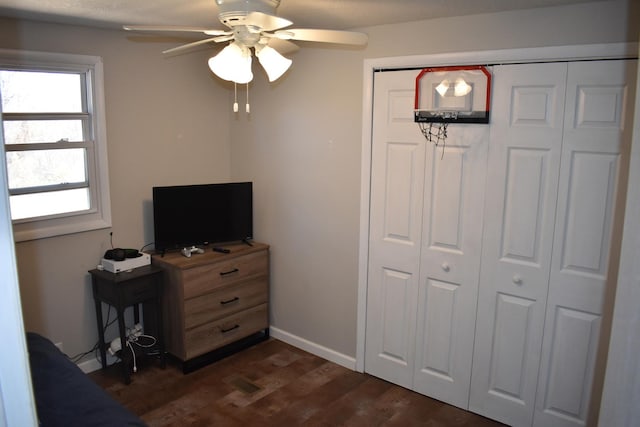 bedroom with a closet, dark wood finished floors, baseboards, and ceiling fan