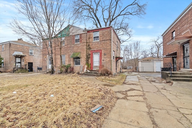 view of front of house featuring an outbuilding, driveway, brick siding, and a garage