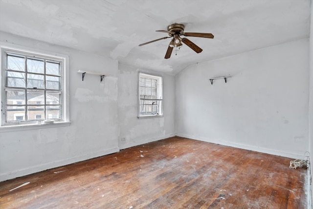 empty room with lofted ceiling, wood-type flooring, baseboards, and ceiling fan