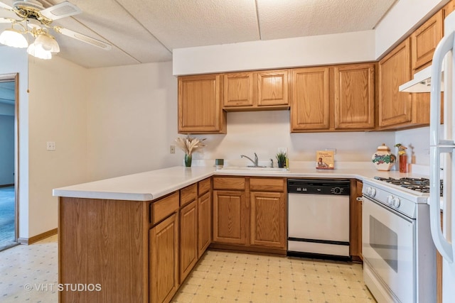 kitchen featuring light floors, light countertops, a peninsula, white appliances, and a sink