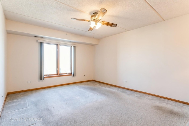 empty room with baseboards, light colored carpet, a ceiling fan, and a textured ceiling