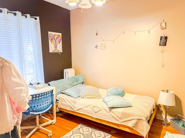 bedroom featuring radiator heating unit, wood finished floors, and baseboards