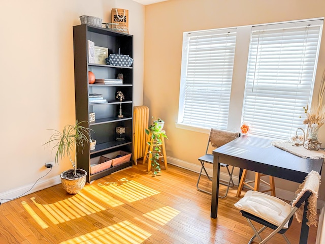 office area featuring radiator, light wood-type flooring, and baseboards