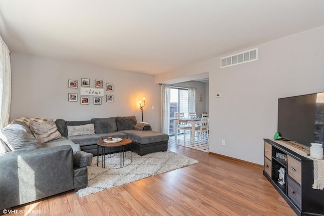 living area with light wood-style floors, visible vents, and baseboards