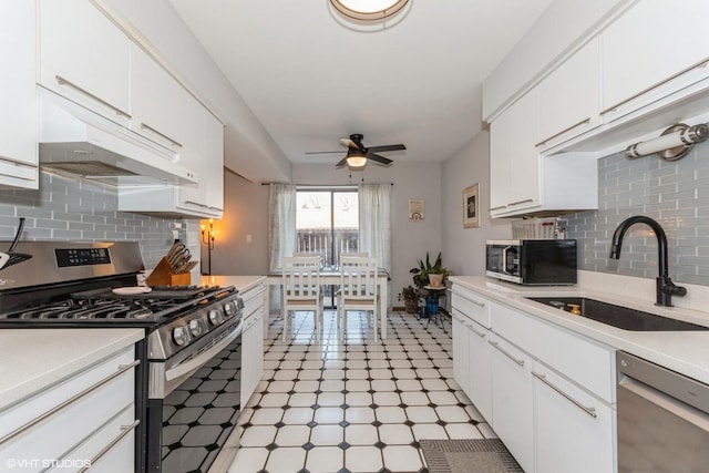 kitchen with a sink, appliances with stainless steel finishes, light countertops, and under cabinet range hood