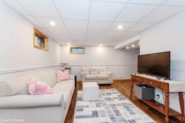 living area with recessed lighting, a paneled ceiling, wood finished floors, and wainscoting