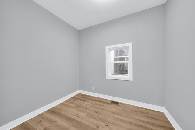 empty room featuring light wood-type flooring, visible vents, and baseboards