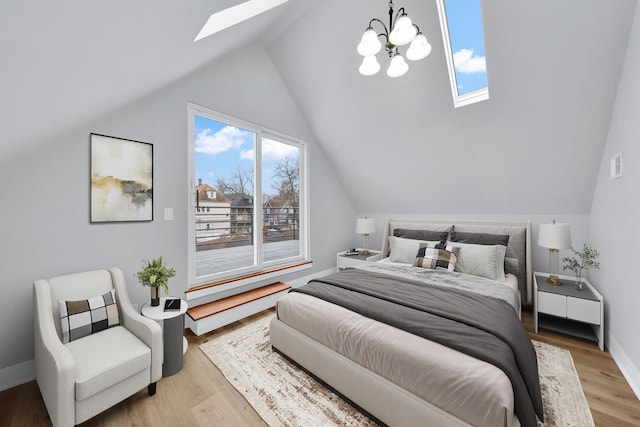 bedroom featuring light wood-style floors, vaulted ceiling with skylight, and baseboards