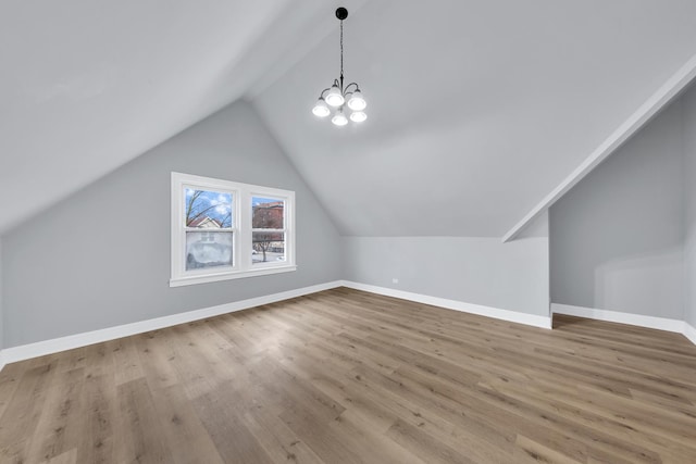 bonus room with a notable chandelier, baseboards, vaulted ceiling, and wood finished floors