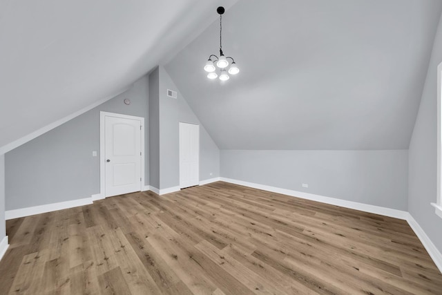 bonus room featuring lofted ceiling, a notable chandelier, baseboards, and wood finished floors