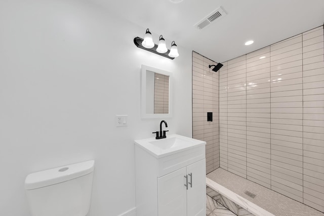 bathroom featuring toilet, visible vents, tiled shower, and vanity