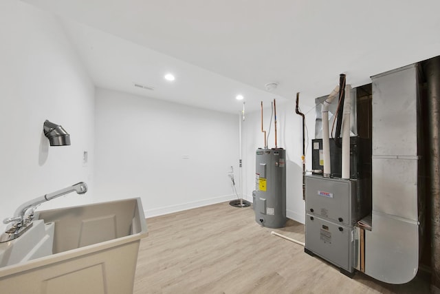 utility room with water heater, visible vents, and heating unit