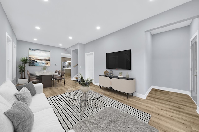 living room with baseboards, light wood-type flooring, stairs, and recessed lighting